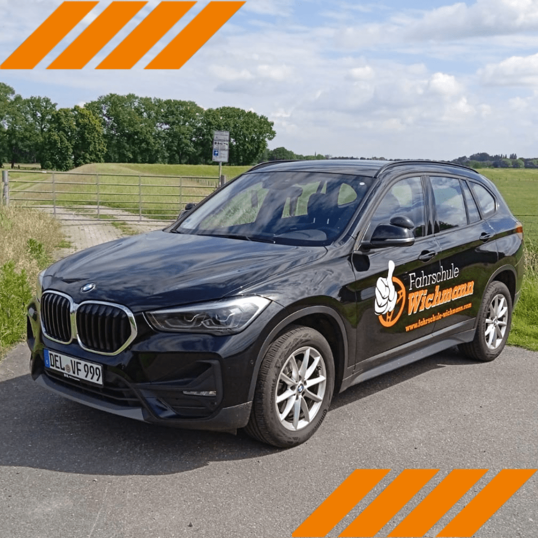 BMW mit Fahrschule Wichmann Logo parkt vor grüner Wiese in Rastede
