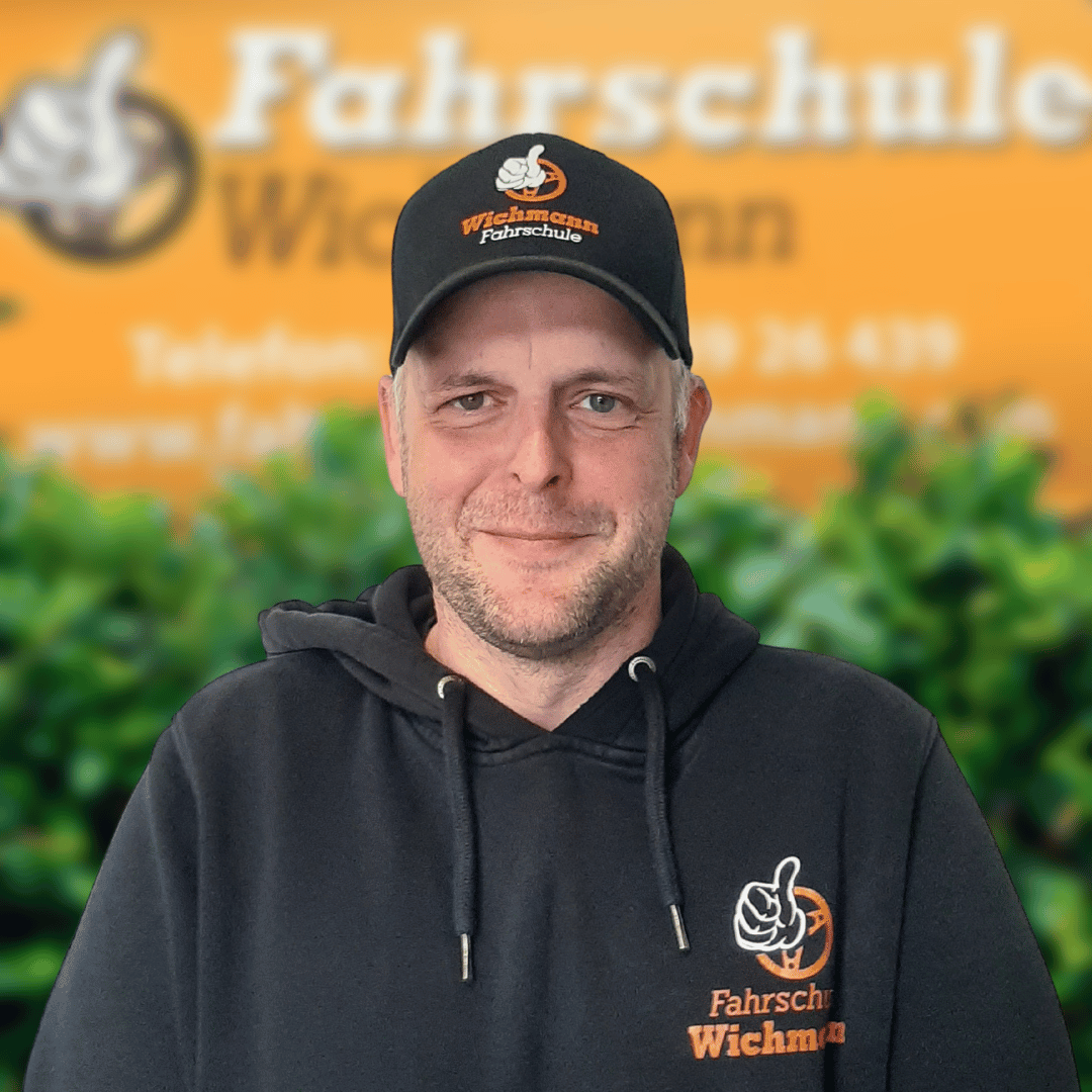 Fahrlehrer mit Kappe und Pullover der Fahrschule Wichmann vor Rastede-Standort