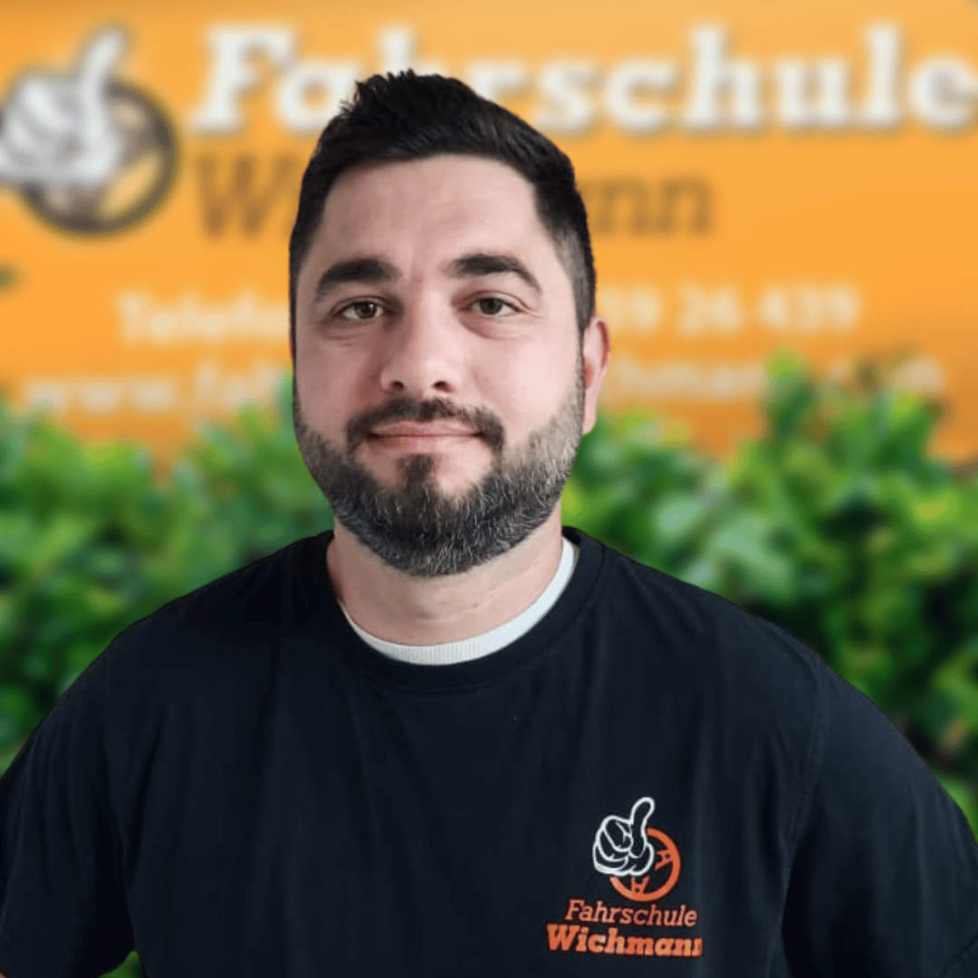 Fahrlehrer der Fahrschule Wichmann Rastede vor gelbem Logo-Hintergrund
