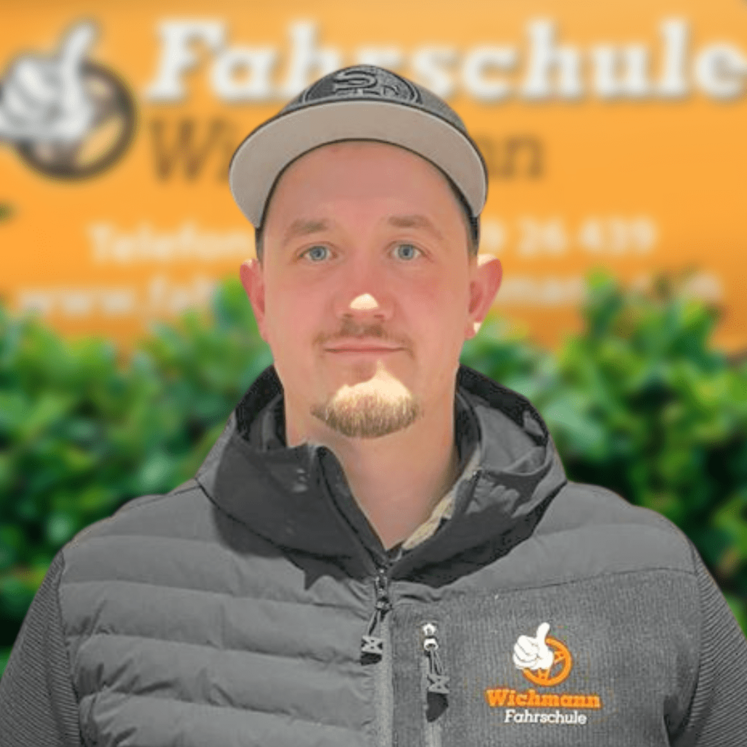 Fahrlehrer mit Kappe vor Fahrschule Wichmann Schild am Standort Rastede