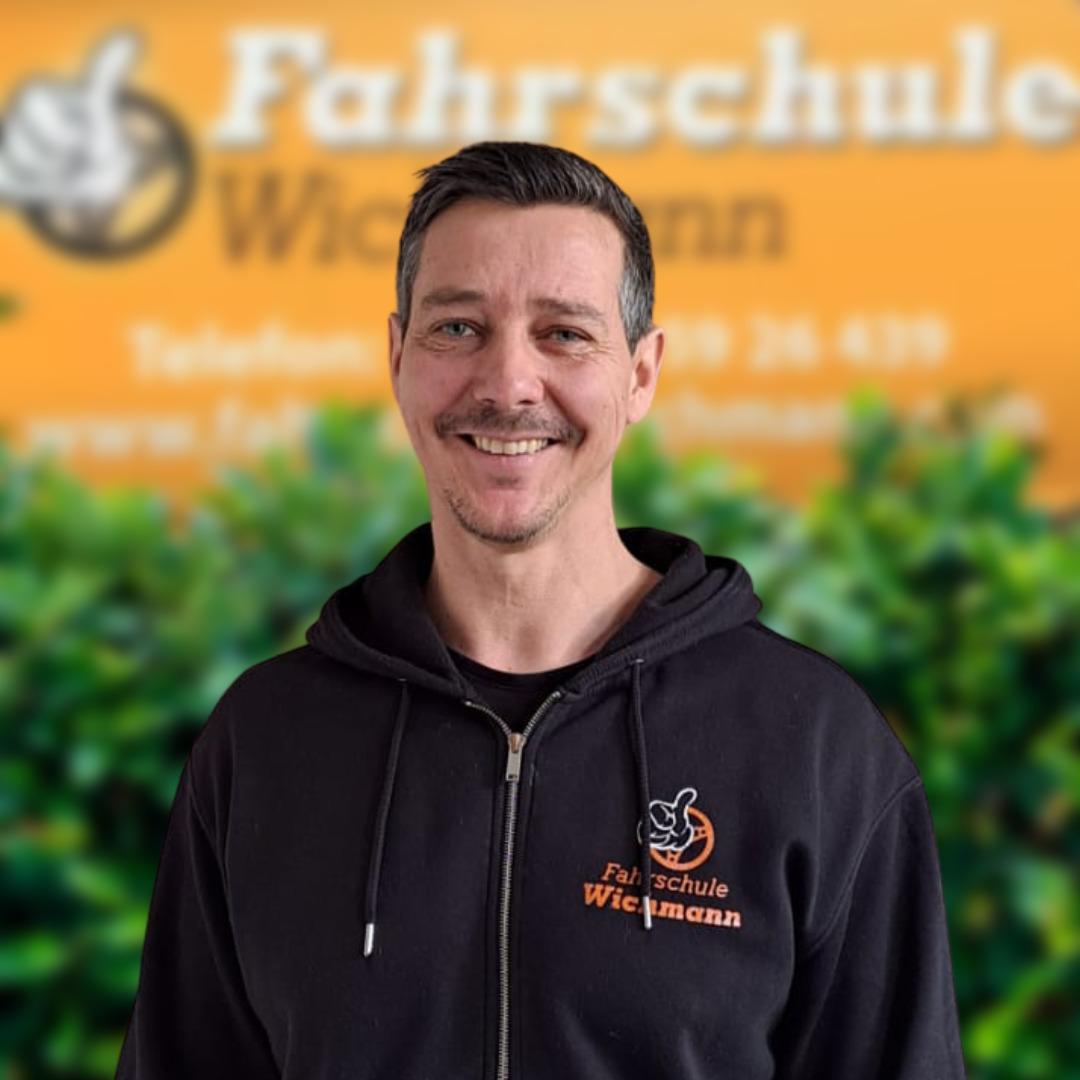Fahrlehrer vor dem Logo der Fahrschule Wichmann am Standort Rastede
