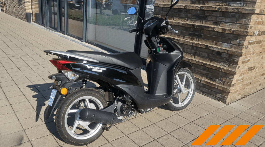 Schwarzer Motorroller vor moderner Fahrschule Wichmann Rastede auf gepflastertem Platz