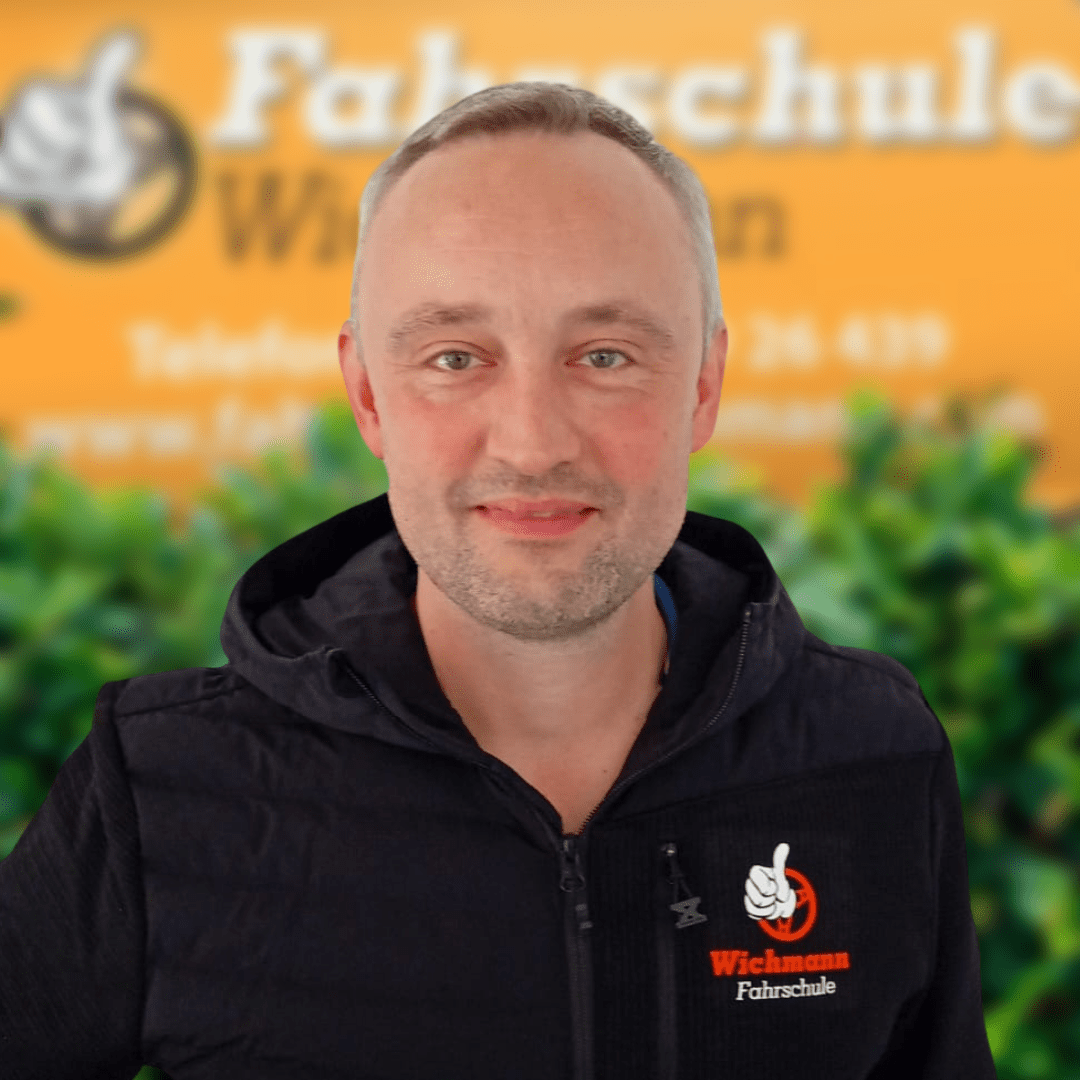 Fahrlehrer der Fahrschule Wichmann in Rastede mit Logo vor orangenem Hintergrund