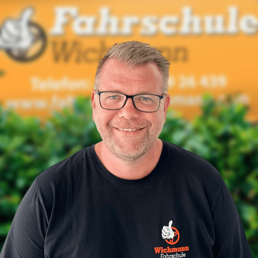 Fahrlehrer mit Brille und schwarzem Shirt vor Fahrschule Wichmann Rastede