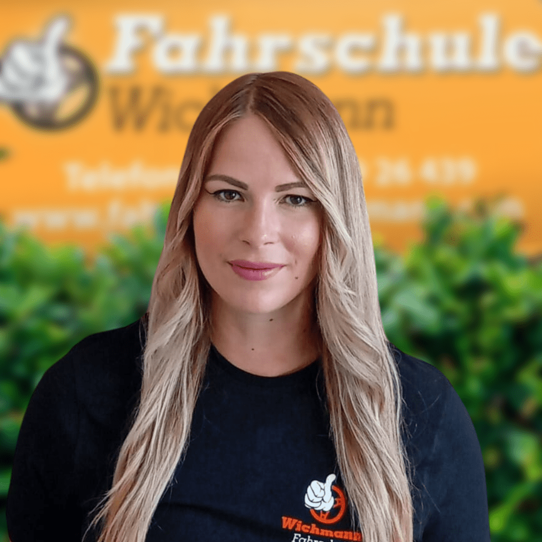 Fahrlehrerin der Fahrschule Wichmann vor dem Logo am Standort Rastede