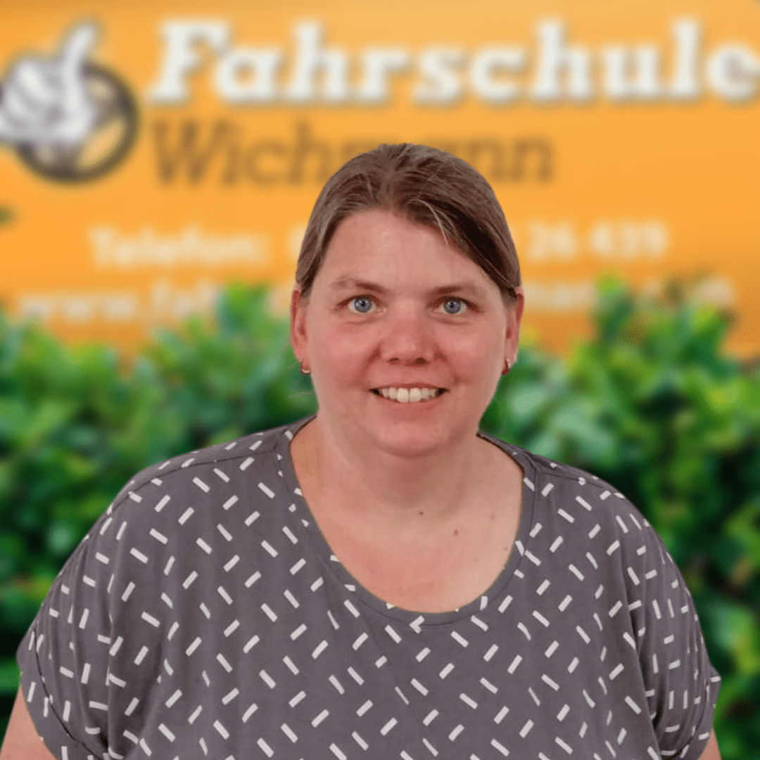 Fahrlehrerin vor gelbem Fahrschule Wichmann Schild in Rastede