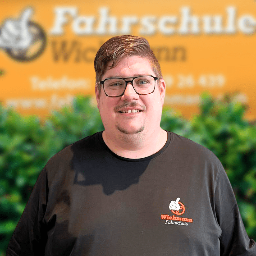 Fahrlehrer Torben vor dem Logo der Fahrschule Wichmann Rastede