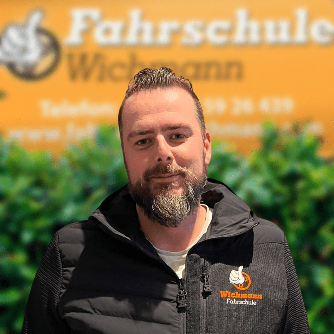 Fahrlehrer Timo der Fahrschule Wichmann in Rastede vor orangem Schild