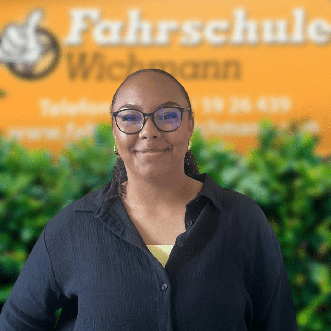 Charline von der Fahrschule Wichmann Rastede vor orangem Logo und grünen Pflanzen