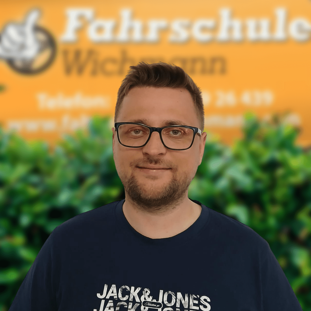 Fahrlehrer Mirco vor dem Firmenschild der Fahrschule Wichmann in Rastede