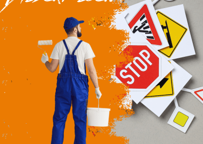 Maler mit Farbe vor Verkehrszeichen und Schriftzug bei der Fahrschule Rastede