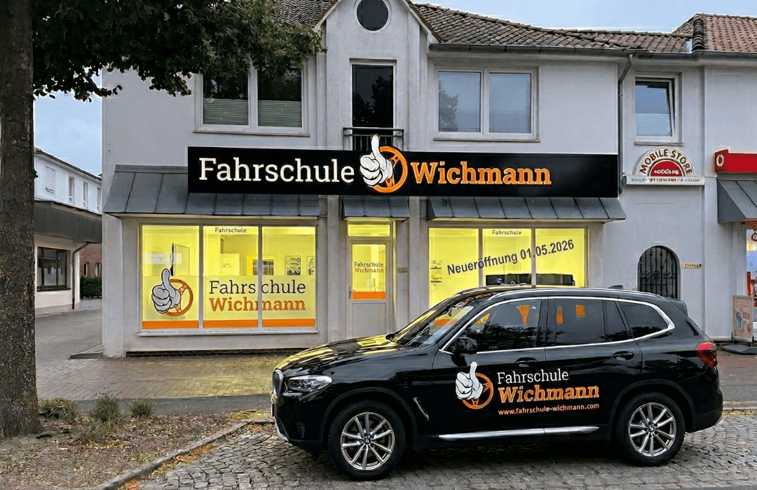 Fahrschule Wichmann Rastede mit großem Logo und Firmenfahrzeug vor dem modernen Standort